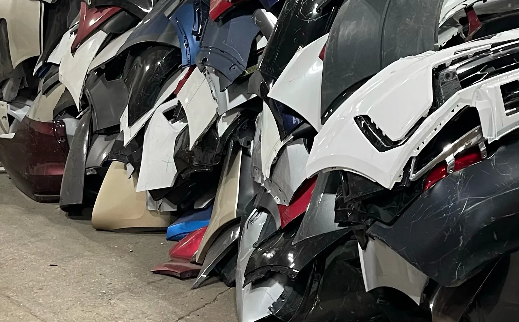 Discarded bumper covers stacked in a collision repair yard